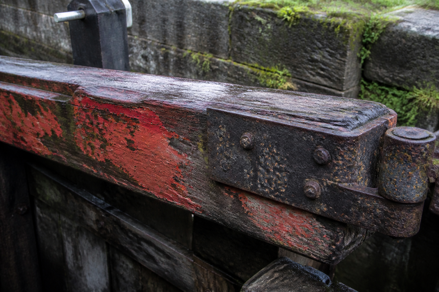Worn beam-red lock gate timber with oxidised iron hinge plate